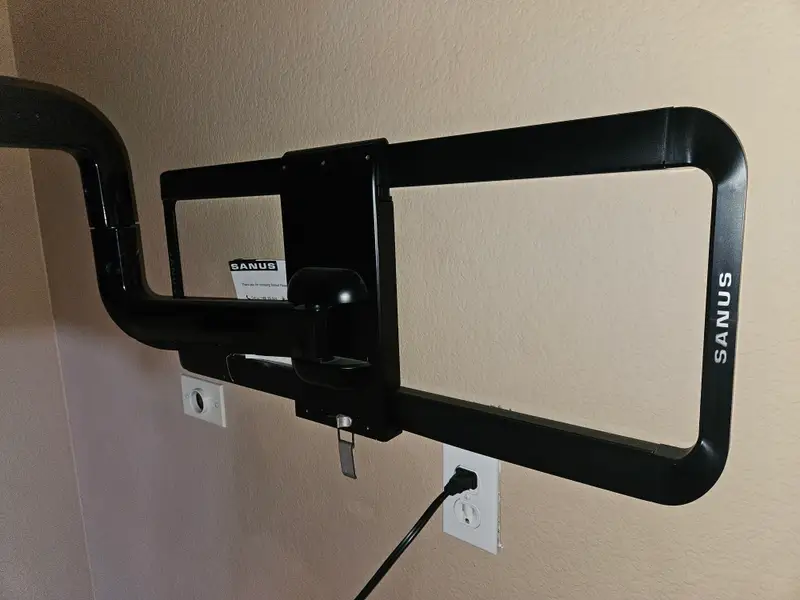 Heavy duty articulating TV mount anchored to the wall above an outlet